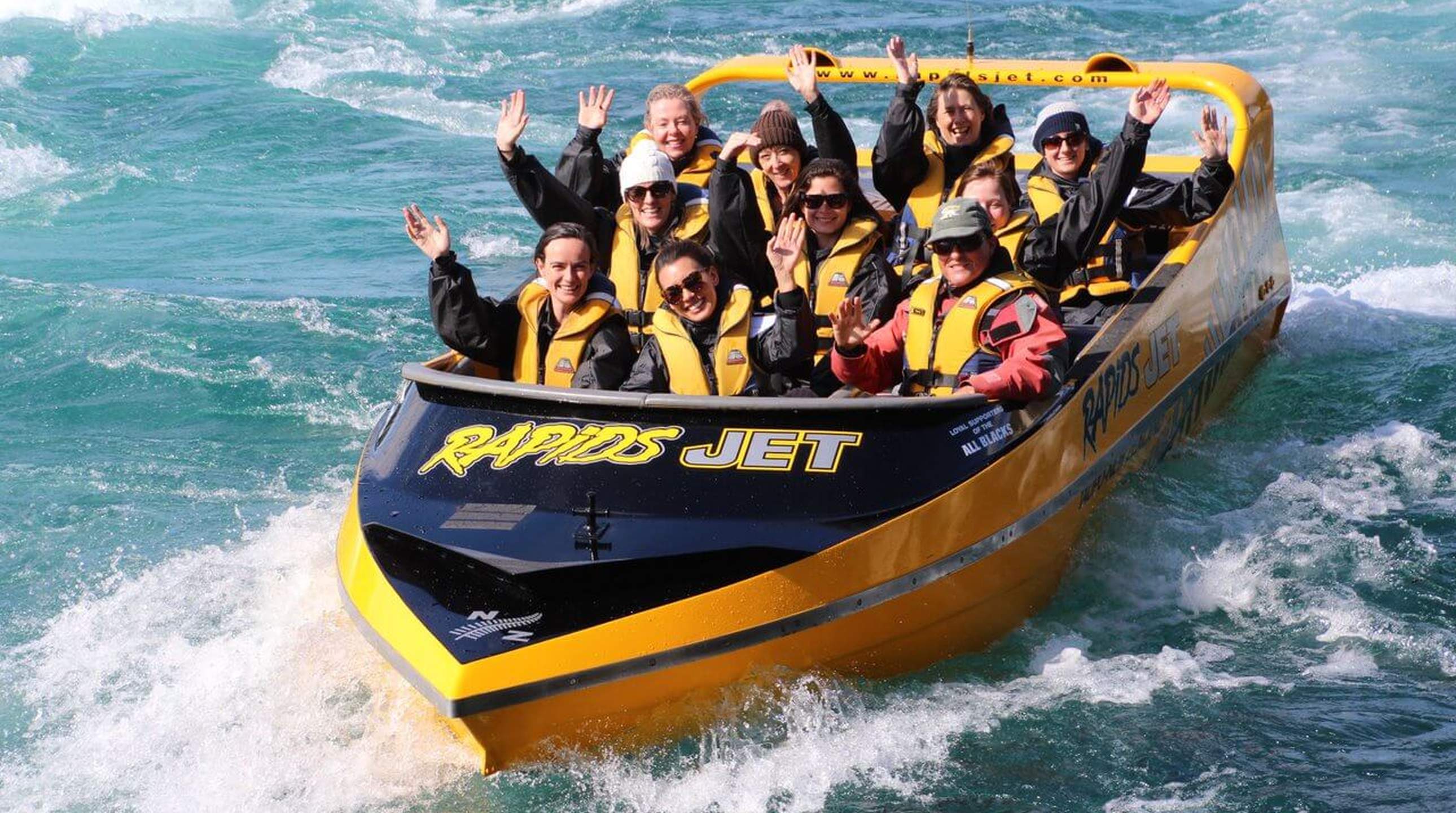 2504_img_taupo_town_rapid_jets_adrenaline_jet_boat_ride_waikato_river_people_in_boat_waving_large_2580x1440